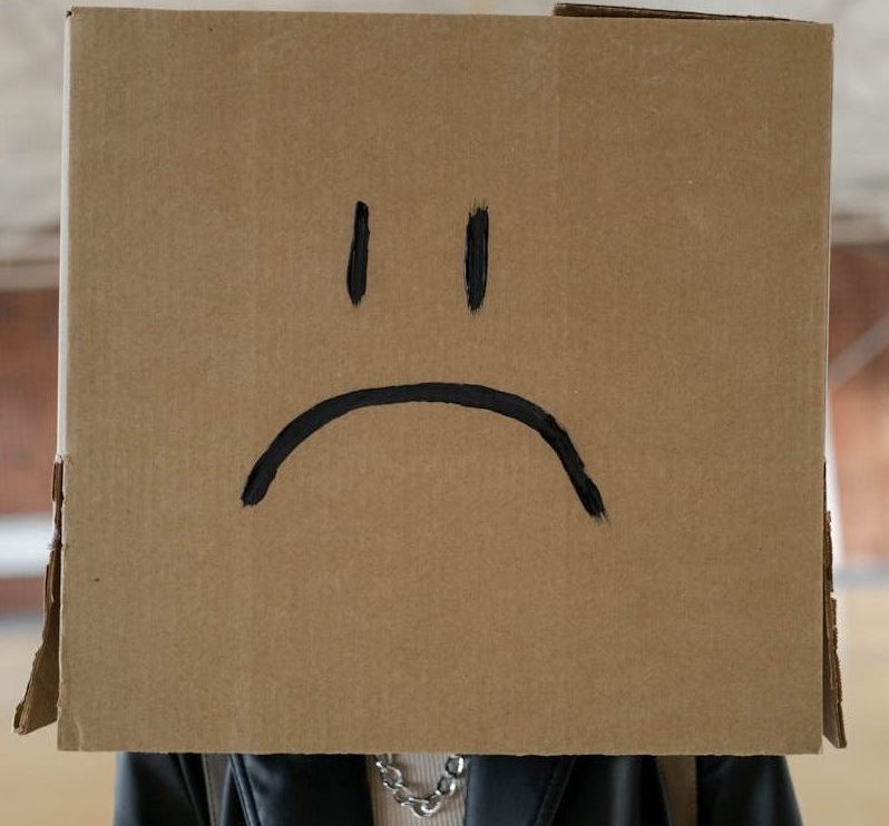 attitude woman with a box on her head with a sad face drawn on it