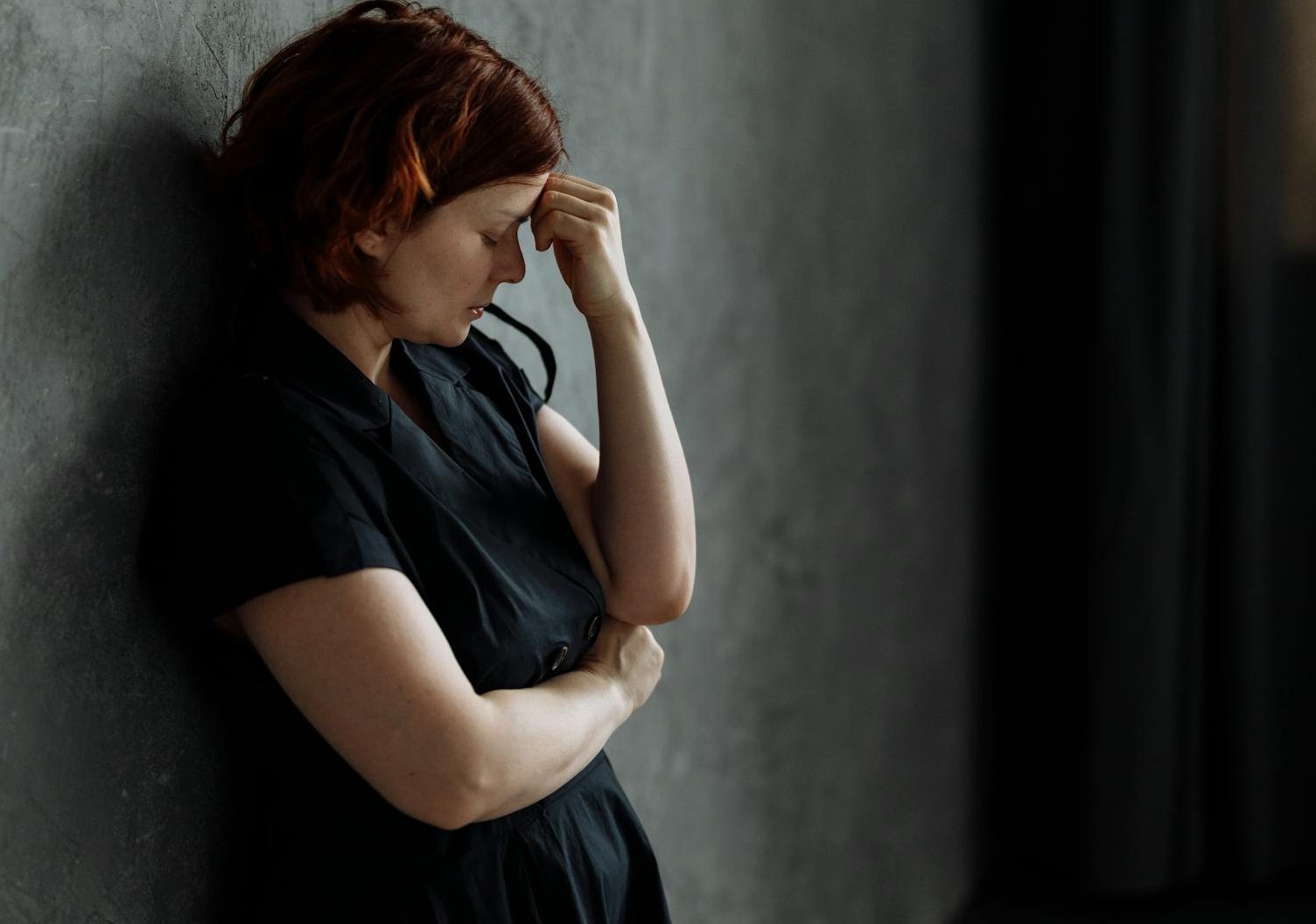 a depressed woman leaning on a concrete wall