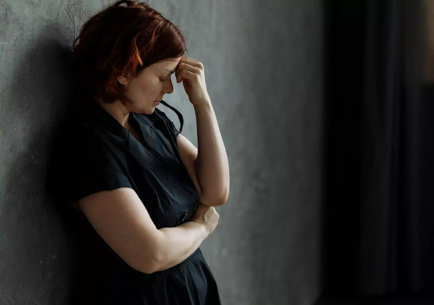 a depressed woman leaning on a concrete wall